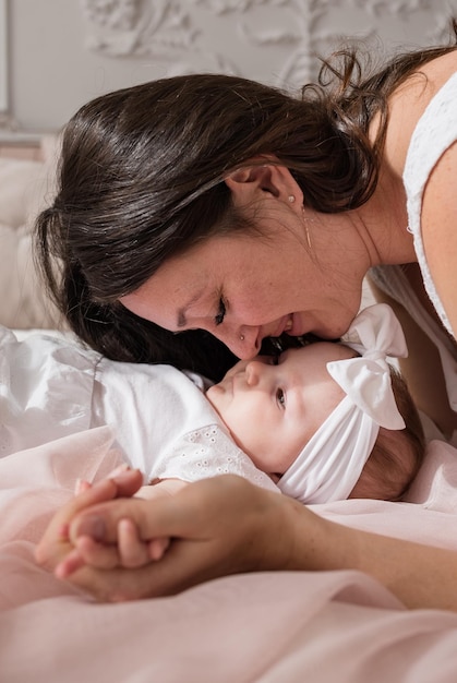 Mama und Baby liegen auf dem Bett im Zimmer und spielen im Zimmer