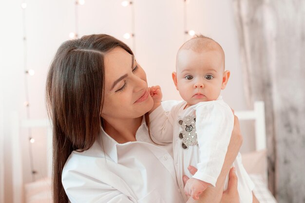 Mama und Baby spielen im Schlafzimmer und halten es in den Armen