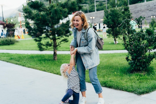 Mama und ihre kleine Tochter haben Spaß im Park spielen und lachen eine glückliche Familie spazieren zusammen
