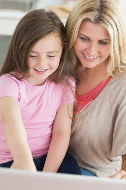 Mama und kind, die am laptop sitzen und lächeln