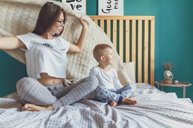 Mama und Kind haben Spaß im Schlafzimmer auf dem Bett, spielen unter der Decke