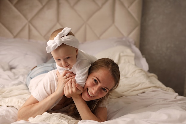 Mama und kleine Tochter kuscheln auf einem weißen Laken Mutterschaft