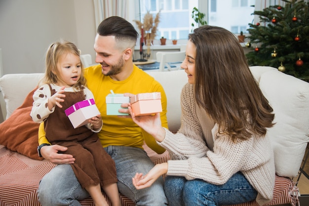 Mama und Papa Unboxing Geschenk für kleine Tochter zu Hause in der Weihnachtszeit. Familie zusammen feiern neues Jahr.