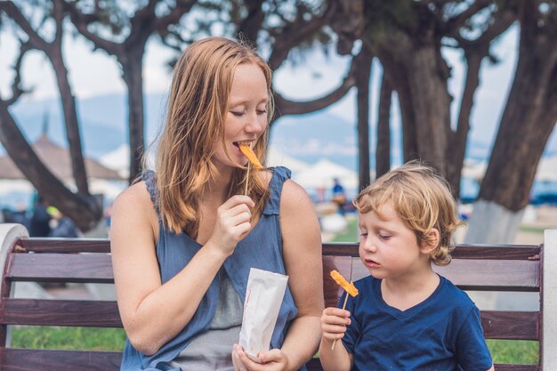 Mama und Sohn essen gebratene Süßkartoffeln im Park