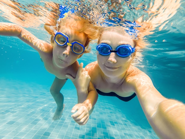 Mama und Sohn in Taucherbrille schwimmen im Pool unter Wasser