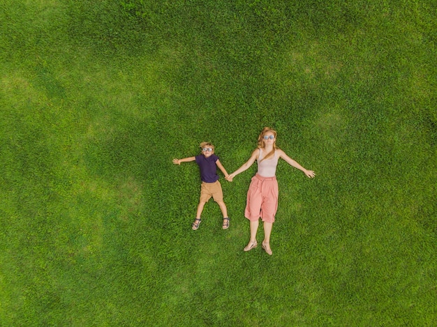 Mama und Sohn liegen auf dem Gras im Park Fotos vom Drohnen-Quadracopter