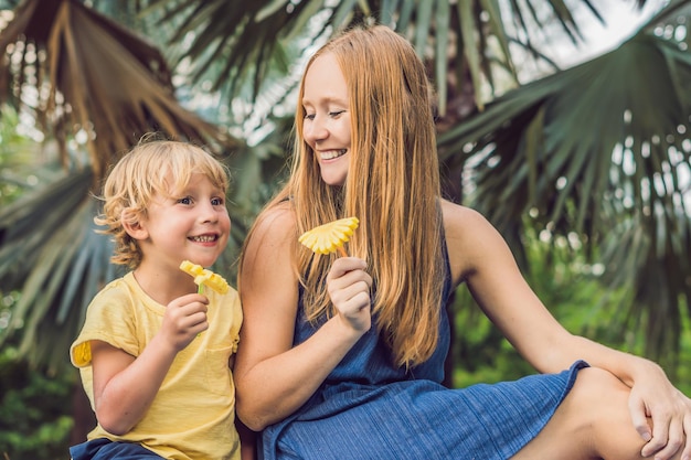 Mama und Sohn machten ein Picknick im Park. Essen Sie gesunde Früchte - Mango, Ananas und Melone. Kinder ernähren sich gesund