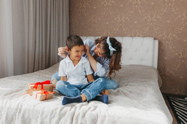 Mama und Sohn sitzen auf dem Bett, umarmen sich und haben Spaß. Liebevolle Mutter und Kind zusammen. Schönen Muttertag!