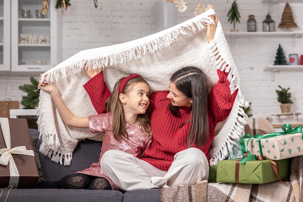 Mama und Tochter auf der Couch im Zimmer unter den Weihnachtsgeschenken