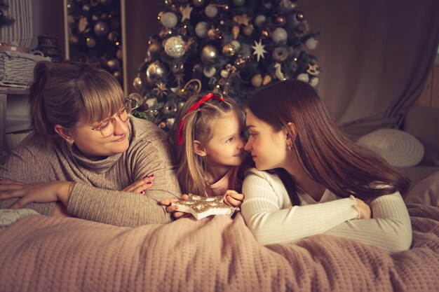 Mama und Töchter liegen im Bett. Weihnachtsschmuck, warten auf den Urlaub.