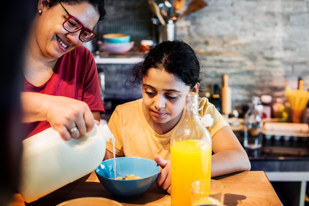 Foto mamá vertiendo leche en el cereal de la hija