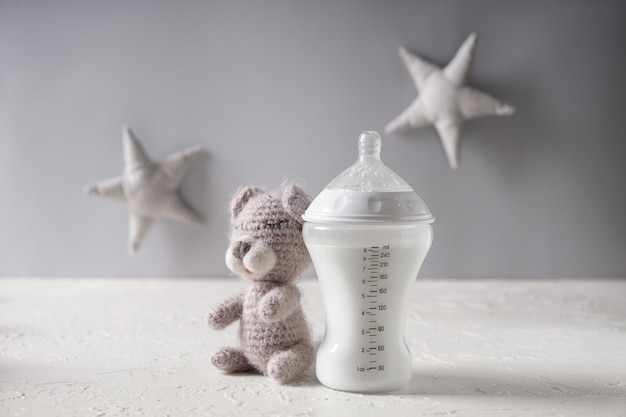 Foto mamadeira com fórmula para bebê e ursinho de pelúcia na mesa branca