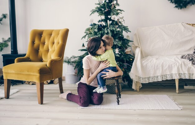 Mamãe abraça a menina no Natal em casa