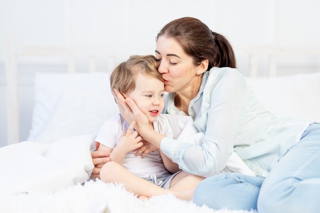 Mamãe abraça bebê em casa na cama, conceito de família e filhos, dia das mães