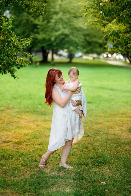 Mamãe abraça e brinca com sua filha de um ano enrolada em uma toalha após o banho.