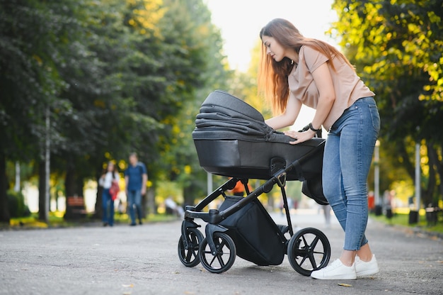 Mamãe andando na rua da cidade. Mulher empurrando seu filho sentado em um carrinho de bebê. Conceito de família.