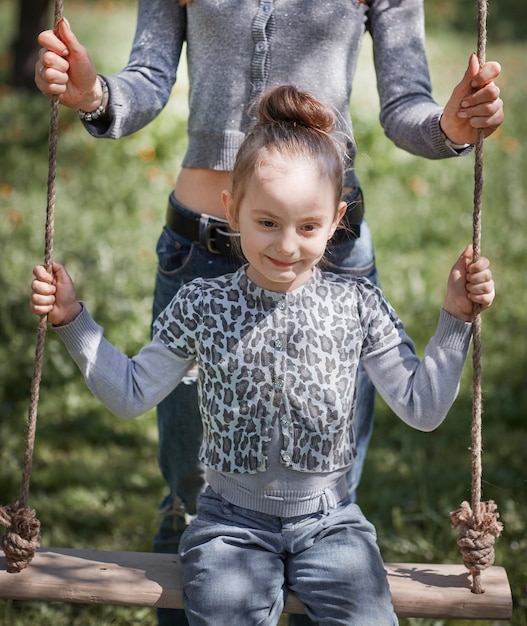 Mamãe balança sua linda filha no balanço