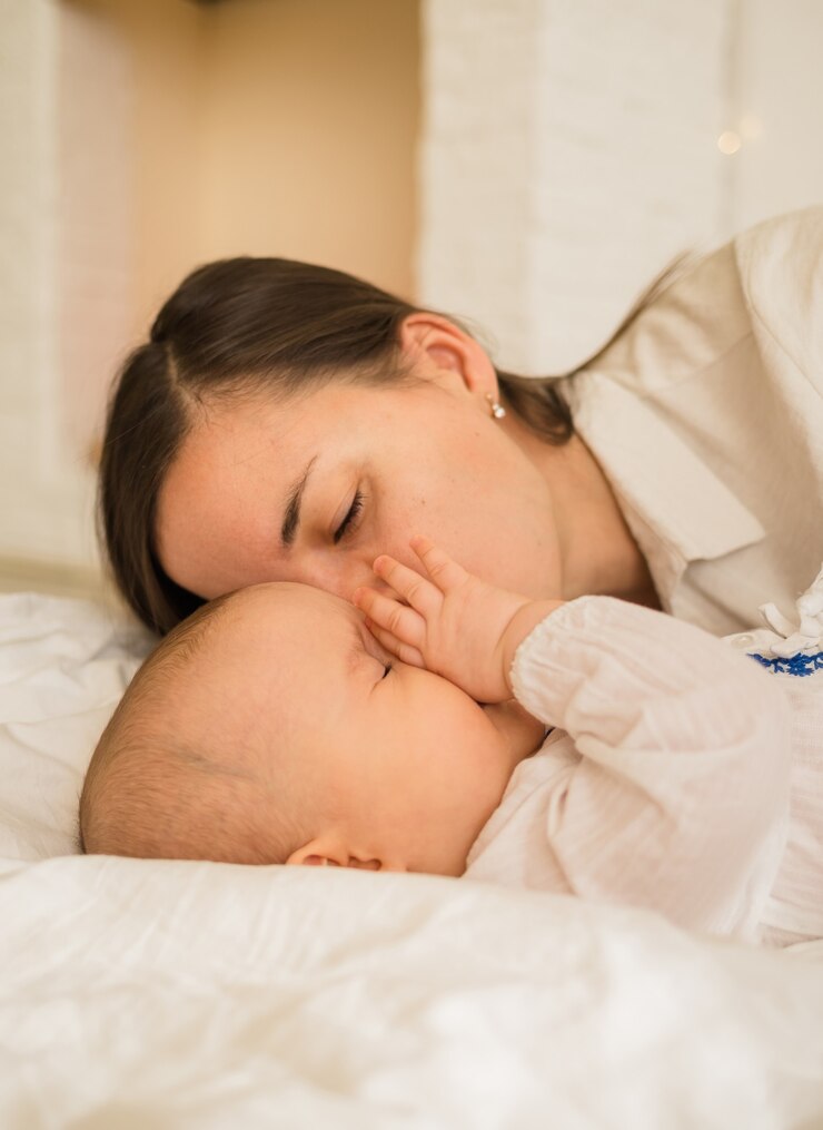 Foto mamãe beija a filha no cobertor branco em cima da cama