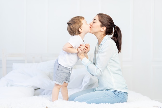 Mamãe beija bebê em casa na cama, conceito de família e filhos, dia das mães