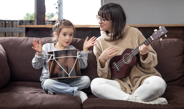 Mamãe brinca com a filha em casa. Aulas de um instrumento musical. Desenvolvimento infantil e valores familiares. O conceito de amizade e família das crianças.