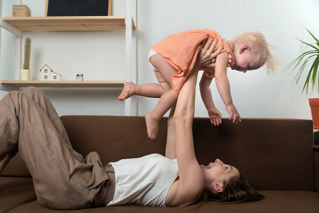 Mamãe brinca com sua filha e a levanta acima dela. Diversão em casa.