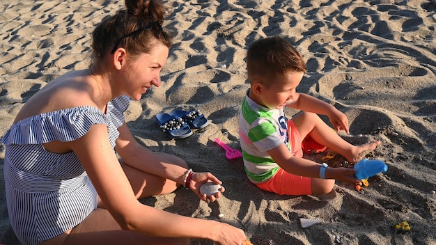 Mamãe brinca com uma criança na vista de cima da praia