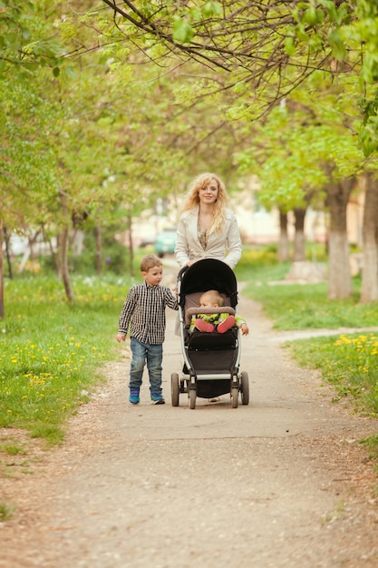 Foto mamãe caminha com a criança em um carrinho de bebê