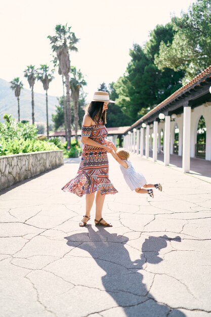 Mamãe circula uma garotinha parada em um caminho pavimentado no parque