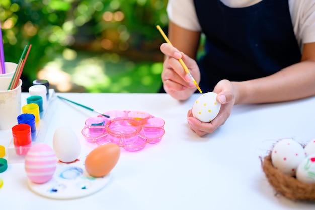 Mamãe colorindo ovos para a celebração da Páscoa em abril. Preparação e pintura para decoração de casa de família.