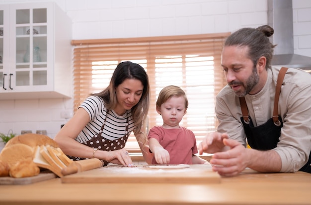 Mamãe e papai na cozinha da casa com seus filhos pequenos Divirtam-se assando pão e fazendo o jantar juntos