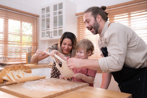 Mamãe e papai na cozinha da casa com seus filhos pequenos Divirtam-se assando pão e fazendo o jantar juntos