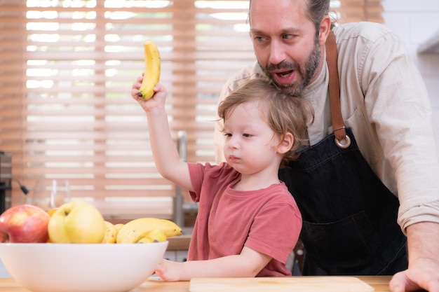 Mamãe e papai na cozinha da casa com seus filhos pequenos Divirtam-se fazendo o jantar juntos