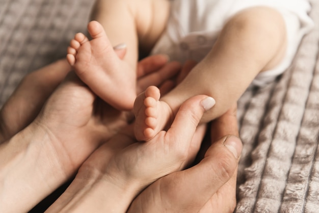 Mamãe e papai segurando pernas de bebês recém-nascidos