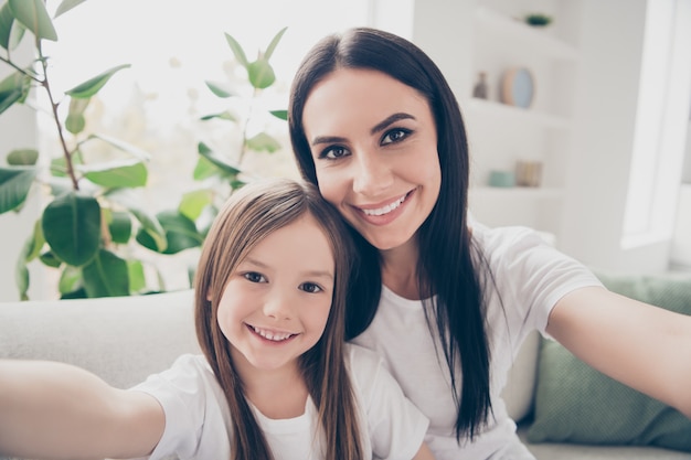 Mamãe e sua filha pequena fazem selfie em casa dentro