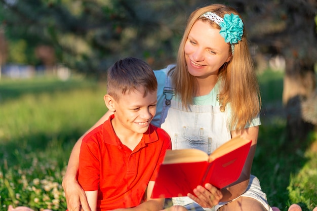 Mamãe está lendo um livro para o filho enquanto está sentada em um cobertor na natureza