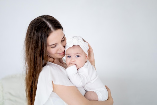 Mamãe está segurando uma pequena menina recém-nascida em casa em um fundo verde Amor materno e espaço de cuidado para texto