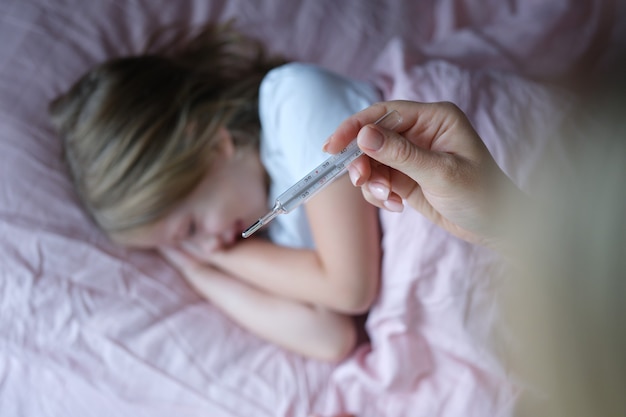 Mamãe mede a temperatura da filha antes de dormir