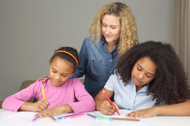 Mamãe observa sua filha desenhando com giz de cera