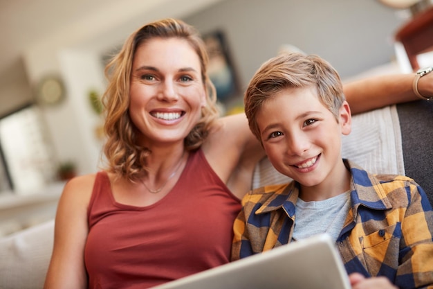 Mamás enseñándome mucho sobre tecnología Foto de un adorable niño usando una tableta digital con su madre en el sofá de casa