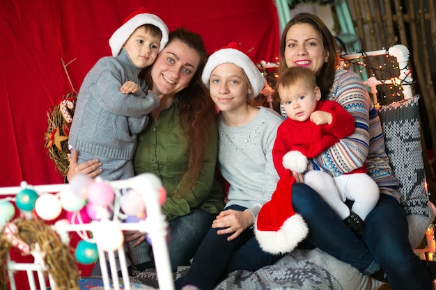 Mamás con niños colgados en una cama decorada para Navidad