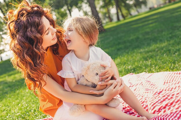 Mami abrazando a su niña y mirando cara a cara en el parque