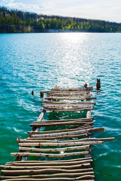 Mampostería de madera se encuentra en el agua aislada. Entrada al lago desde un puente de madera hacia el lago.