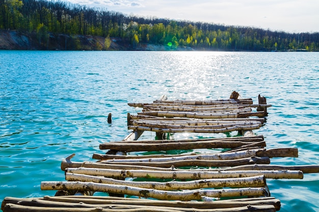 Mampostería de madera se encuentra en el agua aislada. Entrada al lago desde un puente de madera hacia el lago.