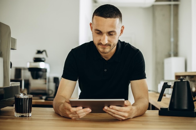 Man Barista mit Tablet am Tresen