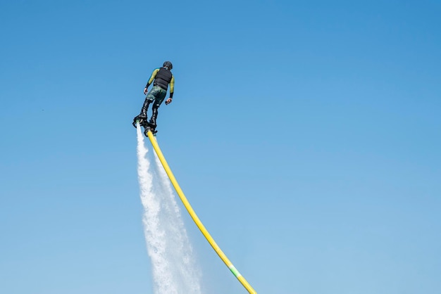 Man fliegt auf einem FlyBoard vor dem Hintergrund des blauen Himmels Extremsport