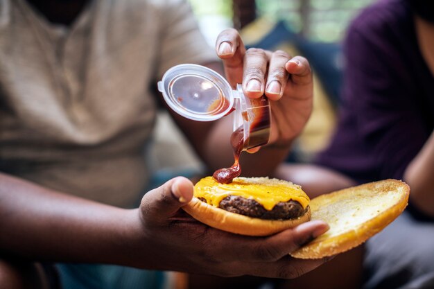 Man fügt einem Burger etwas Ketchup hinzu