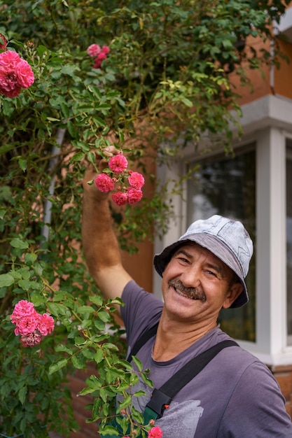 Man gärtner schnitt an einem sonnigen tag den rosenstrauch im wunderschönen garten