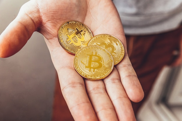Man Hand, die goldene Bitcoin-Münze der Kryptowährung hält