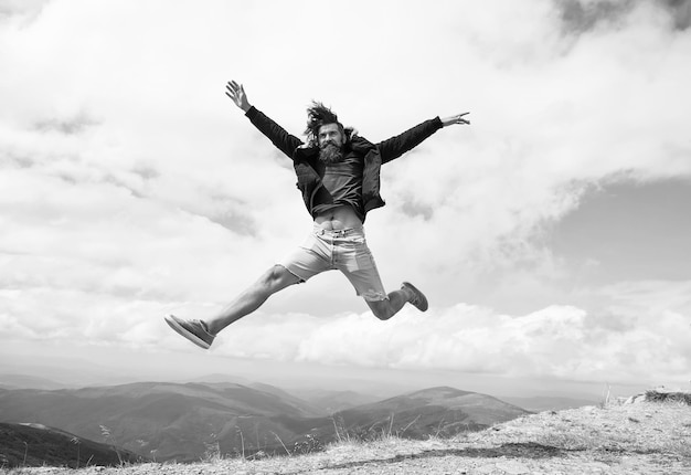 Man Hipster Reisender mit Bart und Schnurrbart springt auf den Berg