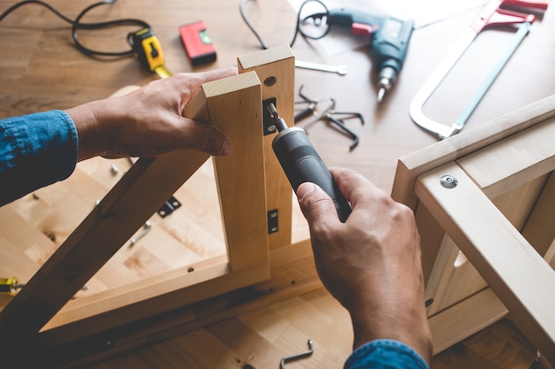 Man montiert Holzmöbel, repariert oder repariert das Haus mit einem Schraubenzieher